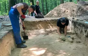 Last, trzej mężczyźni w ubraniach roboczych odkrywają fragmenty ziemi w trakcie prac wykopaliskowych