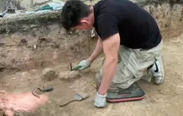 Wykopaliska. Mężczyzna prowadzi prace wykopaliskowe i odkrywa fragmenty ziemi. 
