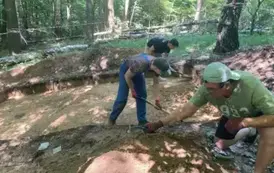 Last, trzej mężczyźni w ubraniach roboczych odkrywają fragmenty ziemi w trakcie prac wykopaliskowych