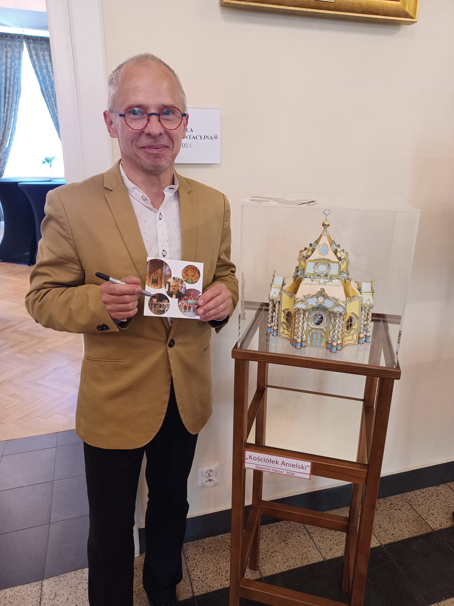 Mężczyzna trzymający wizyt&oacute;wkę obok makieta kości&oacute;łka